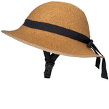 Side-profile view of a straw-hat-style bicycle helmet with a woven texture, black ribbon band tied at the back, and the helmet’s black chin strap, set against a white background.