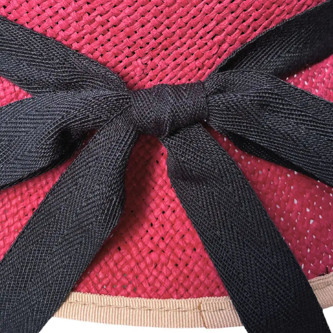 Close up of a red hat with a black ribbon.