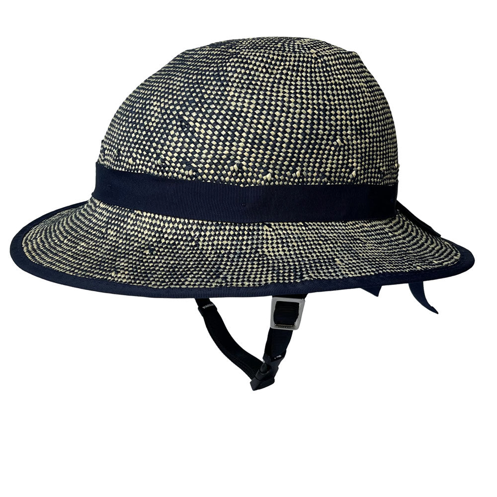 White background product photo. A helmet cover resembles a wide brim straw hat. It's shown installed on a bicycle helmet although only the chin strap of the helmet is visible. The plaiting of the helmet is a mix of off-white and navy blue twists creating a textured effect reminiscent of denim. The product is shown in a front-oriented, three quarter view.